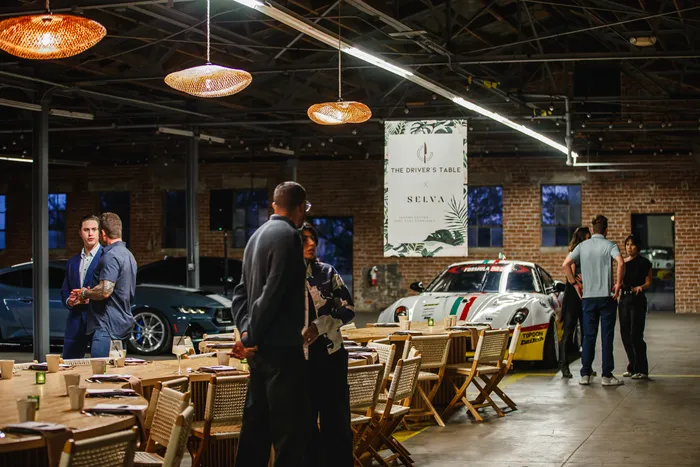 Chef's table dinner under warm pendant lights with a race car on display