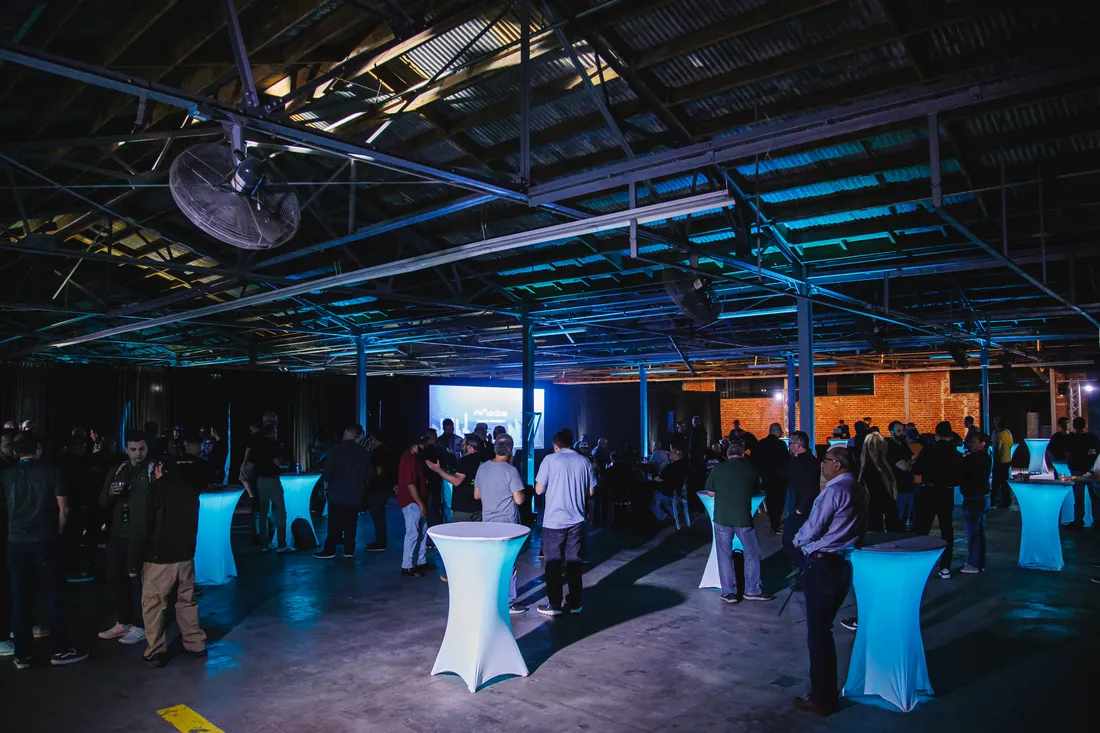 Launch stage with projection screen and acrylic chairs set in the darkened warehouse