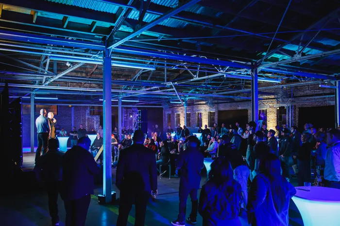 Corporate crowd under blue uplighting between the steel columns