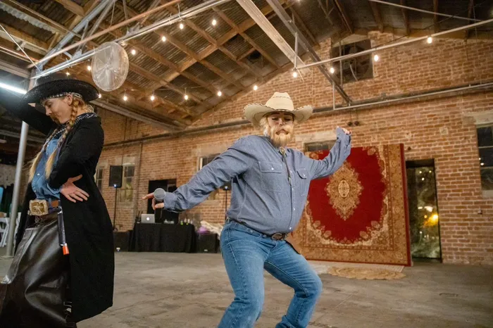 Guests in cowboy hats dancing under string lights