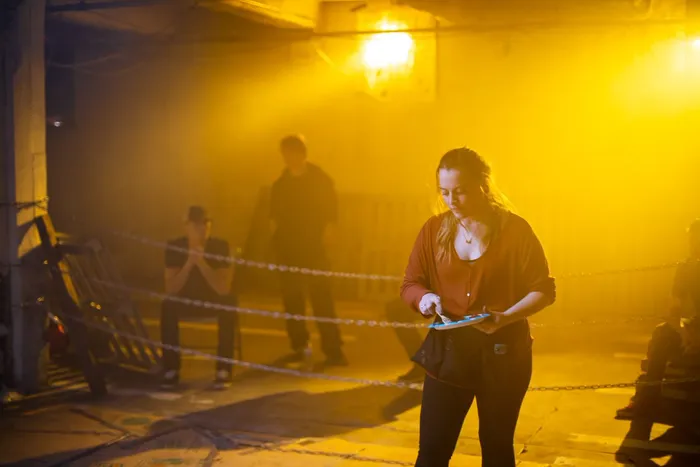 Night shoot in amber haze, actor mid-scene on the warehouse floor