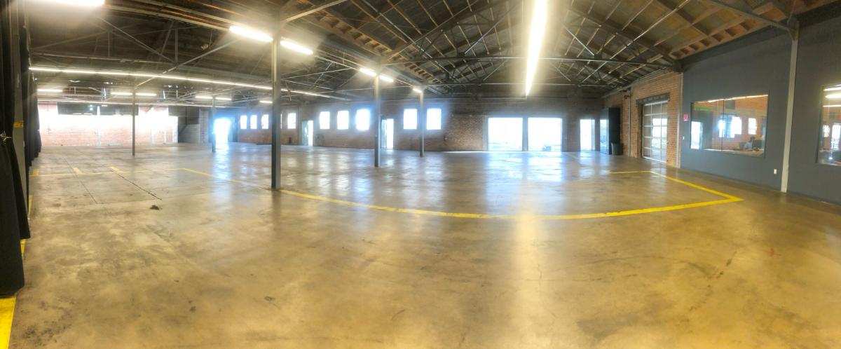 Daylight pouring through the warehouse — steel columns, skylights, and open concrete floor