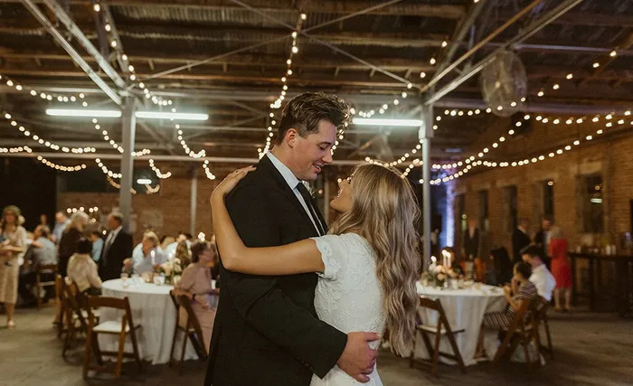 First dance under string lights beside the dinner tables