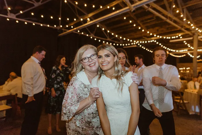 Bride dancing with family as guests look on under string lights