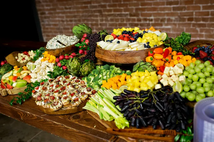 Grazing table piled with fruit, cheese, and charcuterie against the brick wall