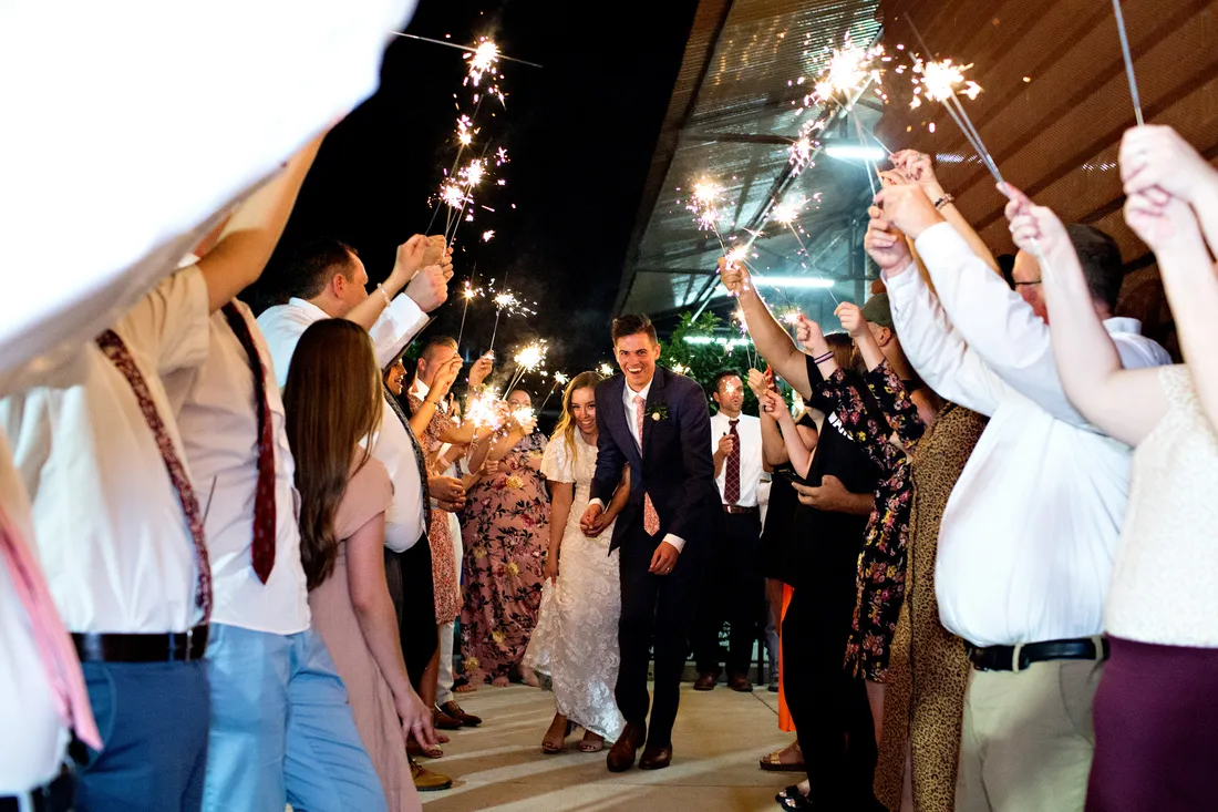 Newlyweds leaving through a sparkler tunnel at night